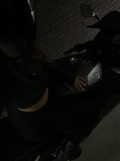 a woman is sitting on a motorcycle in the dark with her hand on the handlebars