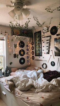 an unmade bed with lots of decorations hanging from the ceiling and lights on the wall