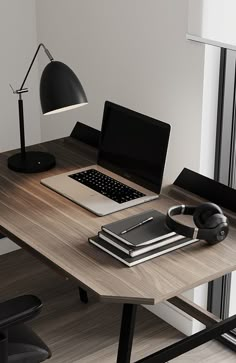 an open laptop computer sitting on top of a wooden desk next to a book and headphones