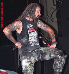 a man with long hair and tattoos sitting on a skateboard