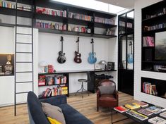 a living room filled with furniture and bookshelves next to a tv mounted on a wall