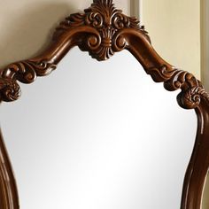 an ornate wooden mirror hanging on the wall