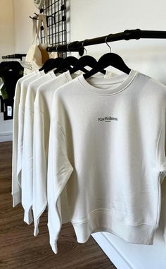 several white sweatshirts hanging on a rack