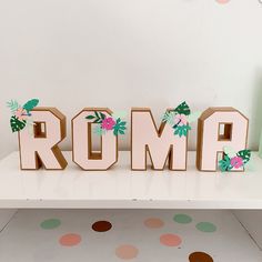 the letters roma are made out of wood and decorated with pink flowers on them