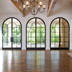 an empty room with three arched windows and wood flooring on the other side of the room