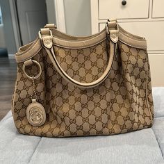 Gucci Canvas Monogram Handbag. Trim Is Winter White Leather. Leather Is In Excellent Condition, The Canvas Has One Small Tear On The Back And A Stain. Inside Is Also Slightly Stained. Purchased From Gucci In 2011. Elegant Bags With Horsebit Detail In Monogram Canvas, Gucci Gold Tote Bag, Gold Gucci Tote Bag, Beige Travel Bag With Horsebit Detail, Beige Gucci Shoulder Bag With Branded Hardware, Gucci Gold Monogram Canvas Bag, Gucci Gold Tote Shoulder Bag, Gucci Gold Shopping Bag, Gold Gucci Shopping Bag