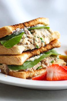 a white plate topped with two sandwiches and fruit