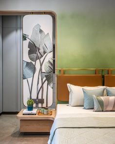 a bed sitting next to a green wall with a painting on the wall behind it