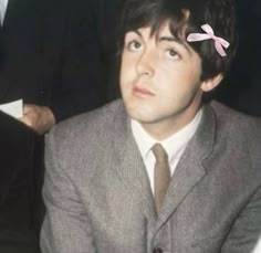 a man wearing a suit and tie sitting in front of another man with a pink bow on his head