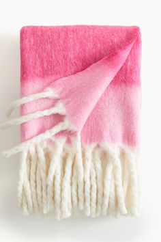 a pink and white blanket laying on top of a table