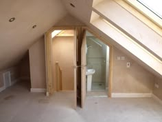 an attic bathroom with skylights and a toilet in the shower stall is seen from the doorway