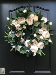 a wreath with white flowers on a black door