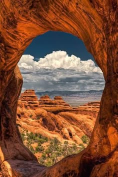 the view from inside a rock formation with clouds in the sky