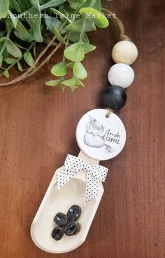 a wooden table topped with black and white beads next to a potted green plant