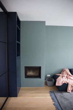 a living room with blue walls and a fireplace in the corner, next to a bed