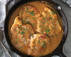 a skillet filled with meat and gravy on top of a table