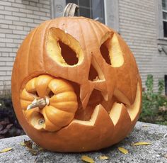 a carved pumpkin sitting on top of a stone slab in front of a house with its mouth open