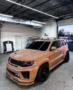 an suv parked in a garage next to another vehicle with pink paint on it's hood