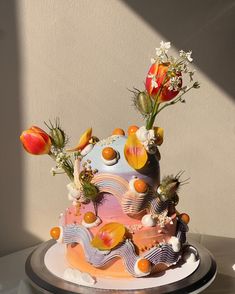 a multi - layered cake with flowers and fruit on top