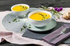 two bowls of soup sit on a place mat