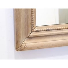 a mirror that is on the wall with bead trimming around it's edge