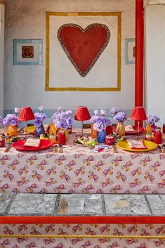 a table topped with lots of plates covered in food next to a red lamp shade