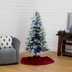 a small christmas tree in the corner of a room with a chair next to it