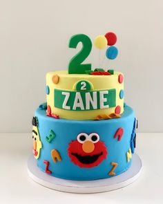 a two tiered cake with sesame street characters on it's top and the number 2