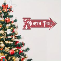 a decorated christmas tree in front of a north pole sign