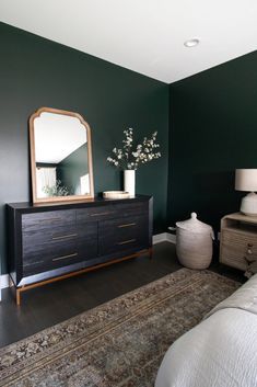 a bedroom with dark green walls and white bedding is shown in the foreground