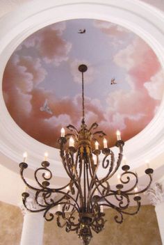 a chandelier hanging from the ceiling in front of a painting on the ceiling