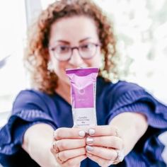 a woman holding up a tube of toothpaste