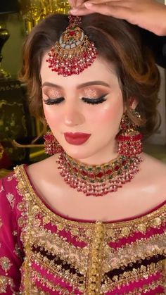 a woman getting her make up done in gold and red