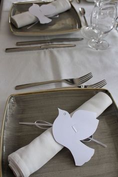 a place setting with napkins, silverware and paper birds on them is ready to be served