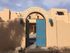 an adobe building with a blue door and arched doorway on the front entrance to it