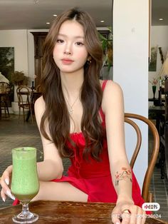 a woman sitting at a table with a green drink