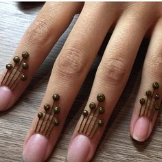 a woman's nails with green beads on them