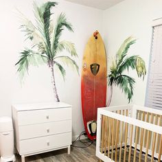 a baby's room with a surfboard painted on the wall and palm trees