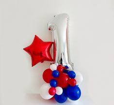 red, white and blue balloons in the shape of an elephant on a table with one balloon