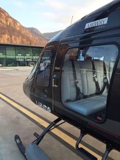 a helicopter sitting on top of an airport tarmac with mountains in the back ground