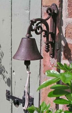 a lamp hanging from the side of a brick wall next to a potted plant