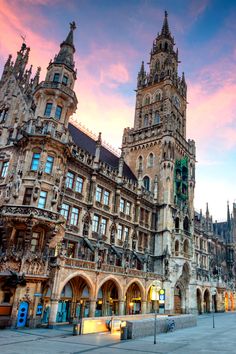 an old building with many windows and towers in the middle of a city at sunset