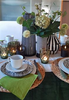 the table is set with plates, cups and vases