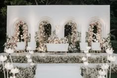 an outdoor wedding setup with white chairs and flowers