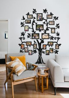 a family tree with pictures on the wall and two chairs in front of it next to a coffee table