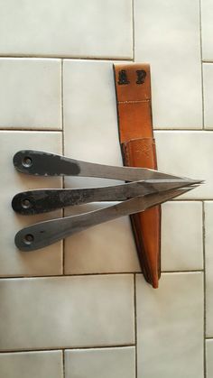 three pairs of scissors sitting on top of a white tile floor next to a knife holder