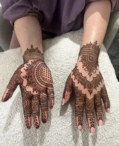 two hands with henna tattoos on them