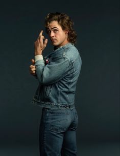 a woman in jeans is posing with her hand on her hip and looking at the camera