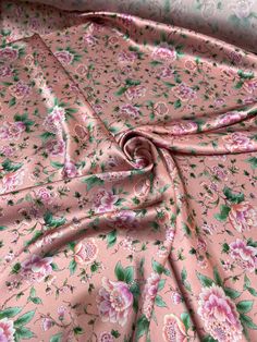 a pink floral print fabric with green leaves and flowers on the bottom half of it