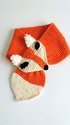 an orange and white knitted scarf with a fox head on it's side